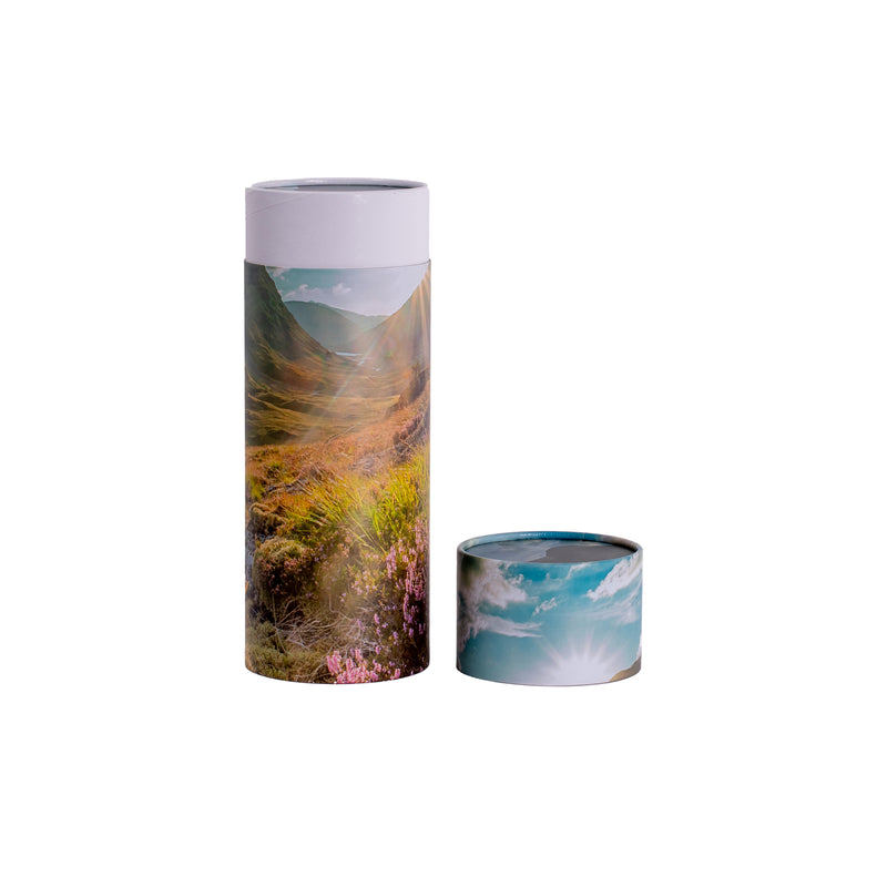 A scatter tube with a mountains design showing the lid removed
